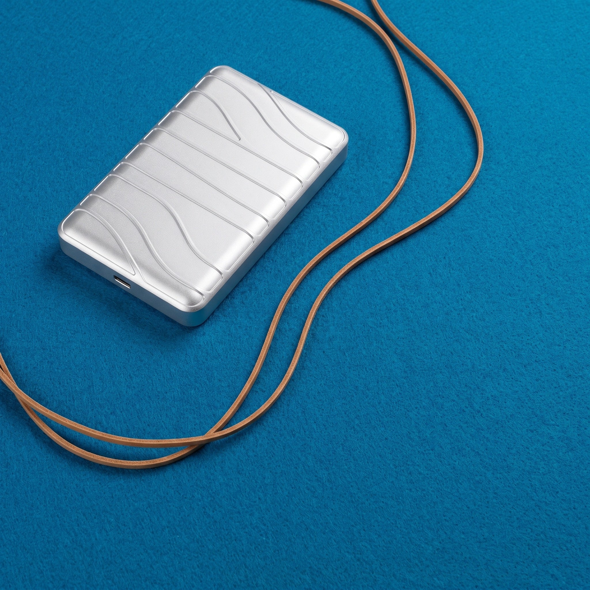 Aria in an overhead flat-lay with a leather cord flowing across azure felt